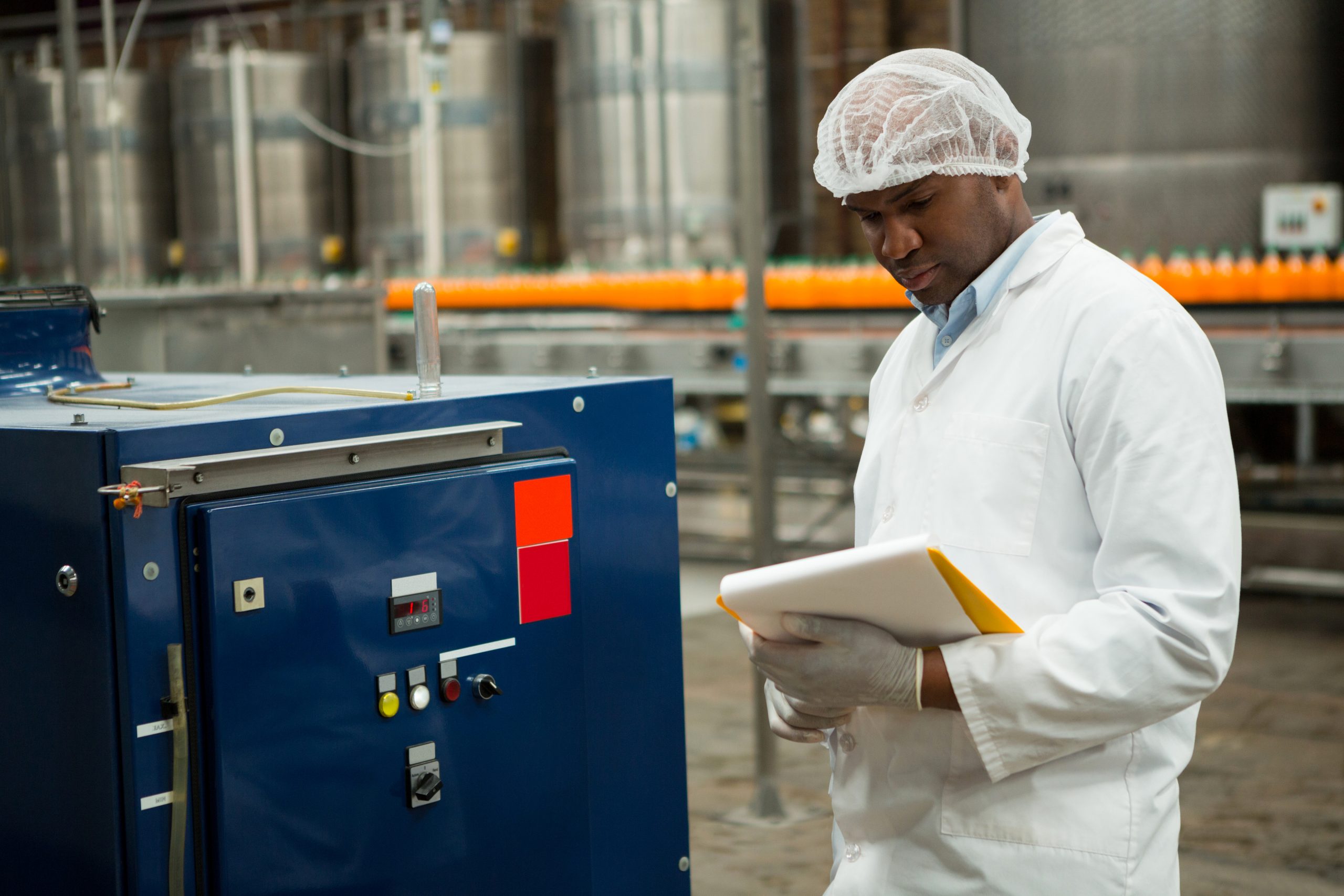Serious male worker inspecting machines at juice factory